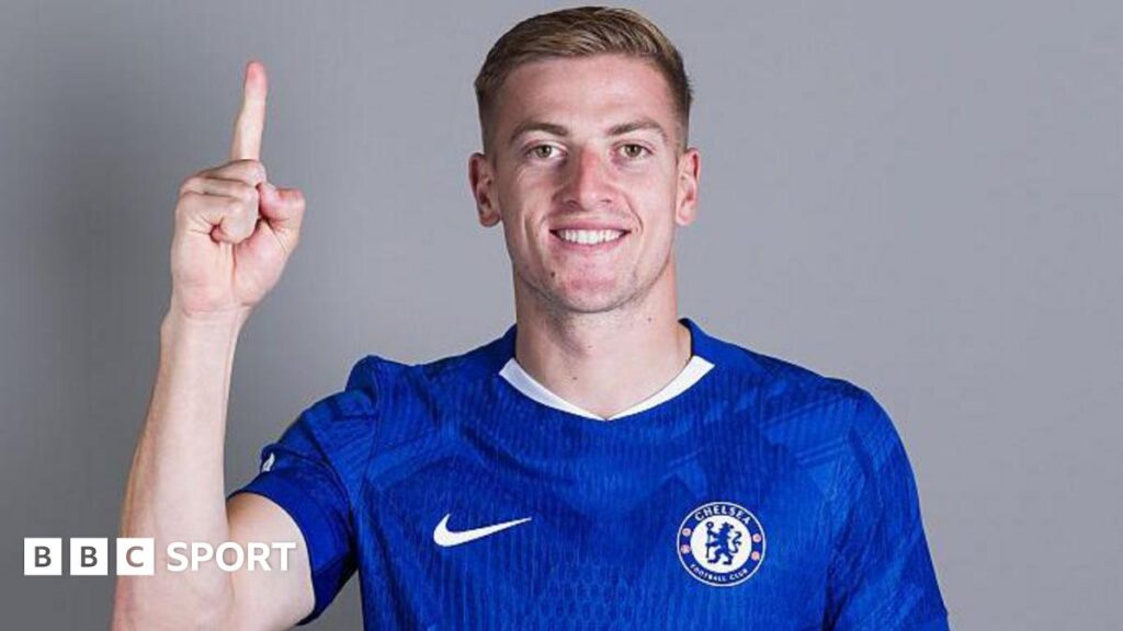 Liam Delap puts his finger up while wearing a Chelsea shirt