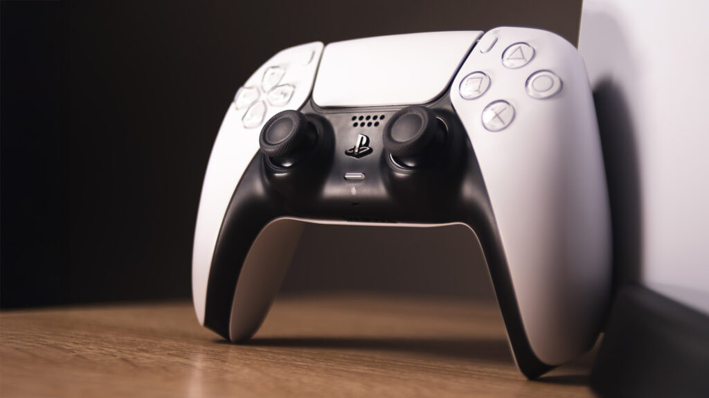 PS5 DualSense controller on a desktop next to a PlayStation 5 console