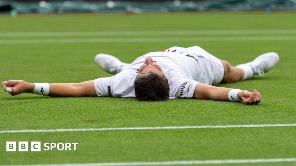 Cameron Norrie celebrates by falling on to the court