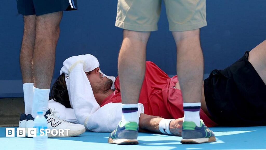 Arthur Rinderknech on his back with an ice pack on his forehead