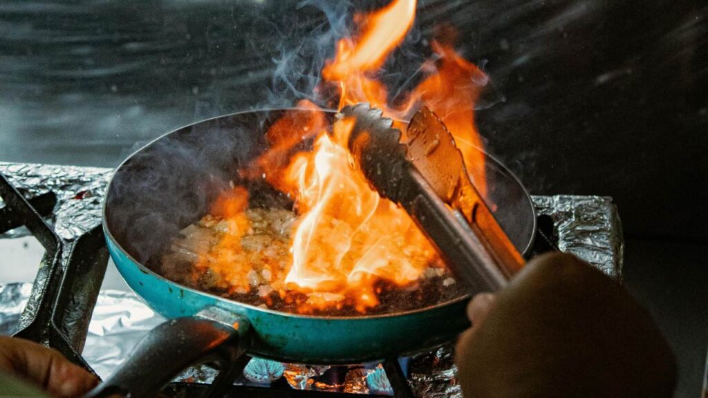 Chef flame cooking on a hot pan