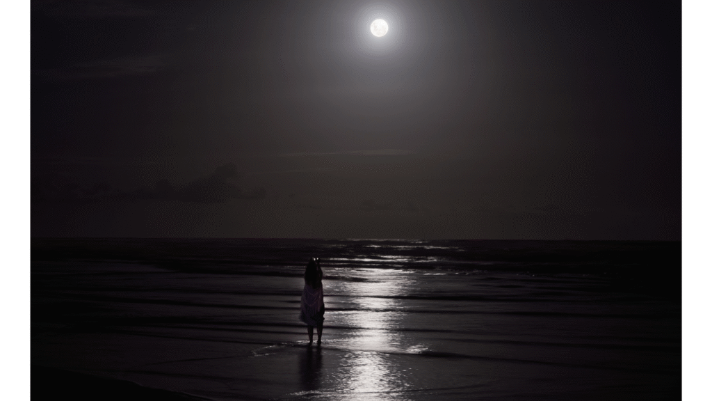 Woman standing on the beach in the light of the full Moon in Aquarius