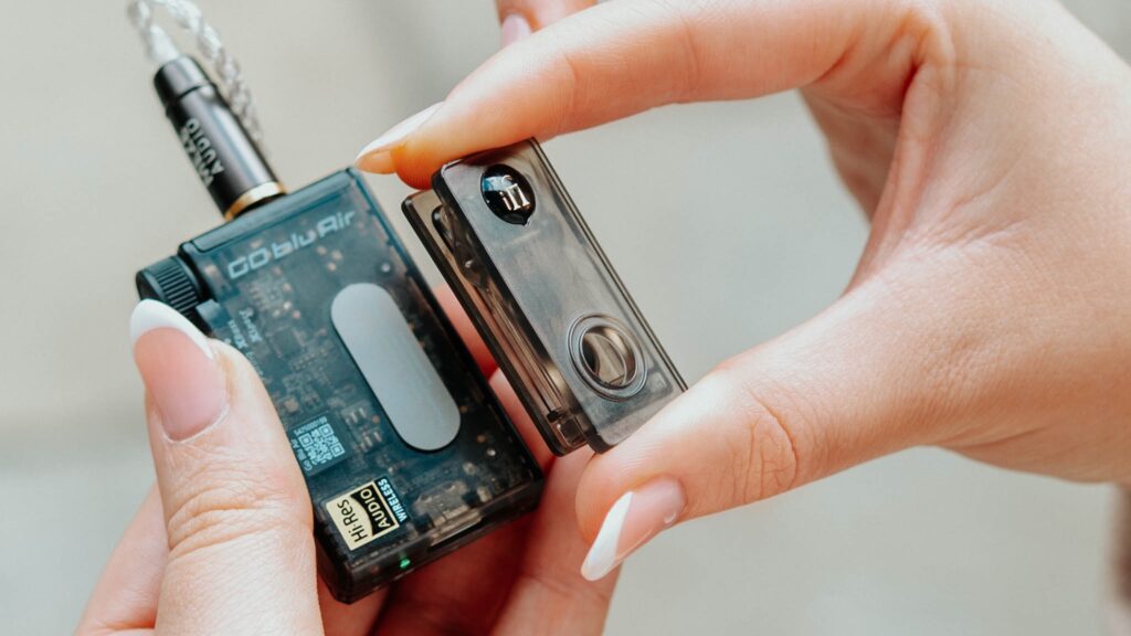 A model's hand holding the iFi Go Blu Air portable Bluetooth DAC