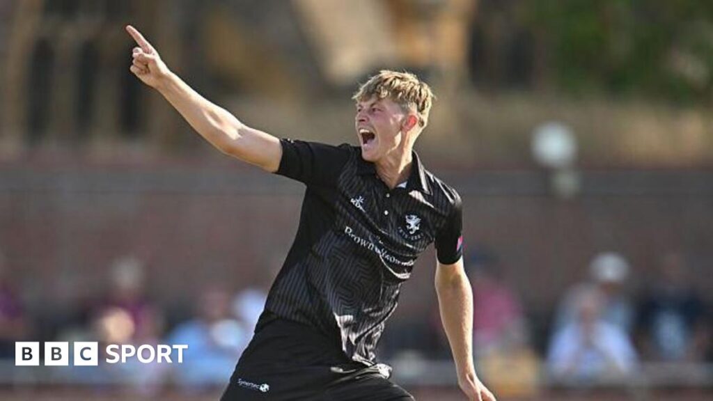 Alfie Ogborne holds one arm in the air in celebration after taking a wicket