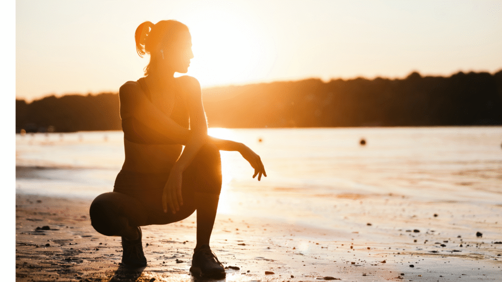 Woman kneeling on the beach watching the sunrise