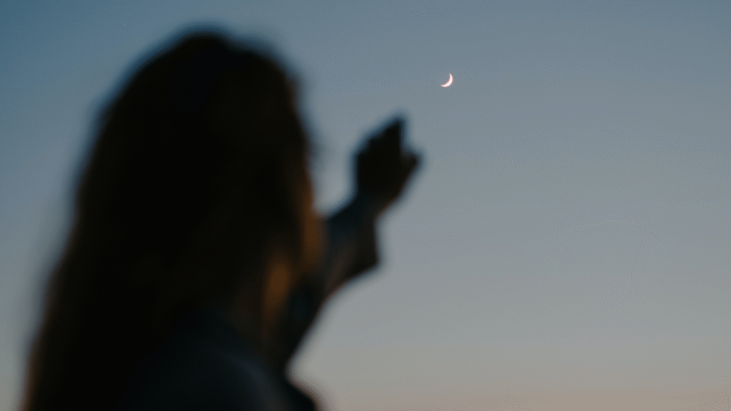 woman pointing at the moon while contemplating the weekly horoscope