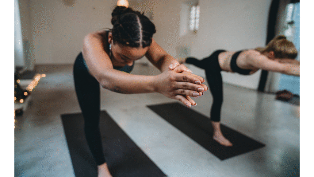 Two yoga students practicing Warrior 3 with their arms extended