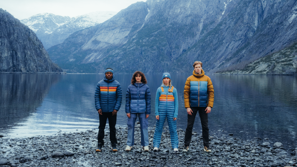 group wearing colorful jackets in front of mountain lake