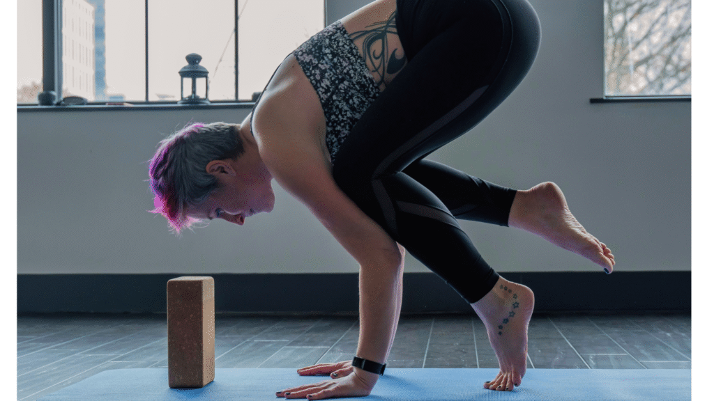 Woman on a yoga mat leaning forward onto a block