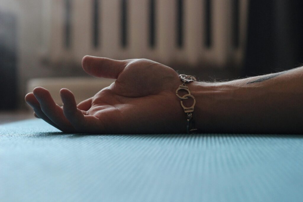 Person's hand reaching out during Savasana on yoga mat.