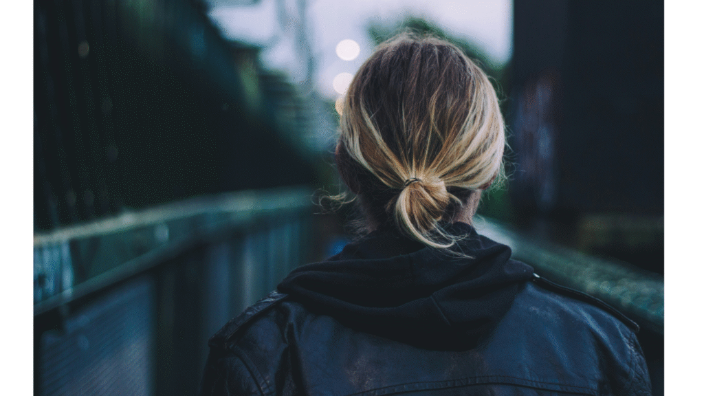 Woman looking away from the camera outside with her blond hair in a ponytail and a coat on